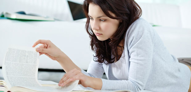 A teenage girl studies while lying on the floor